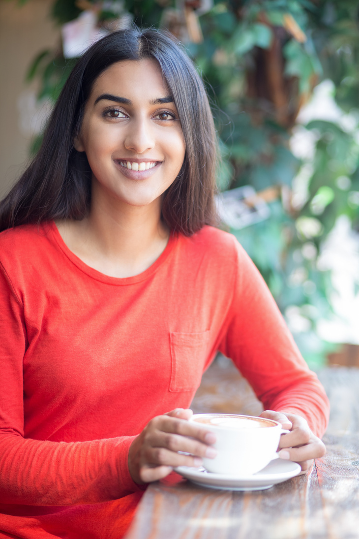 Cheerful Indian Girl in Red Dress Drinking Coffee